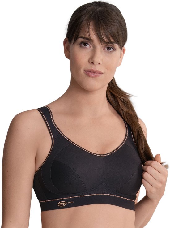 Model van voren in zwarte sportbeha met koperkleurige biezen en Anita Active logo.