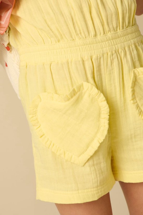 Close-up van een lichtgele playsuit met gerimpelde taille en hartvormige zakken.
