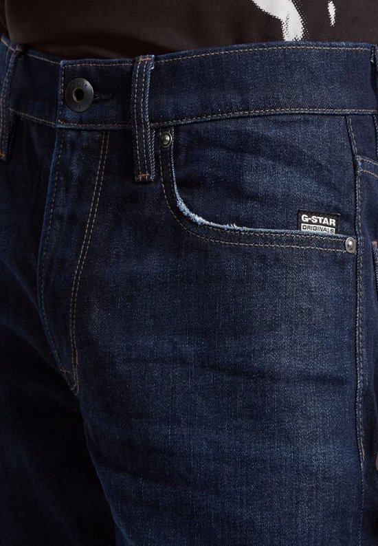 Close-up van een donkerblauwe G-Star jeans met het G-Star Originals label en rafelige rand aan de zak.