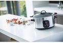 Zilverkleurige Russell Hobbs slowcooker op een aanrecht met ingrediënten op de achtergrond.