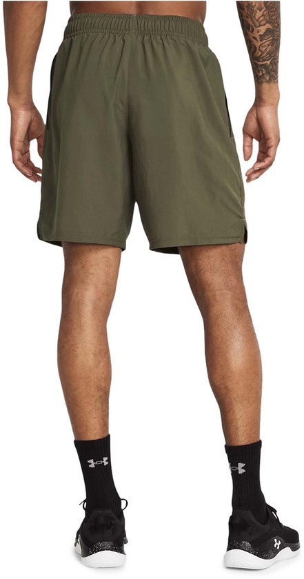 Achterkant van militaire groene sportshort met elastische tailleband, zakken en zwarte schoenen.