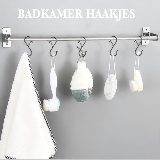 Zwarte S-haken die aan een stang in een badkamer hangen, met een handdoek en badaccessoires.