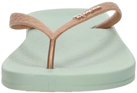 Lichtgroene Ipanema slipper met koperkleurige, golvende bandjes en de tekst "Ipanema" erop.