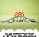 LEGO Duplo treinbaan met oranje bruggen, grijze rails, stationnetje en minifiguur.
