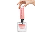 Hand vult Lancôme La Vie est Belle parfum bij uit navulfles. Roze parfum.