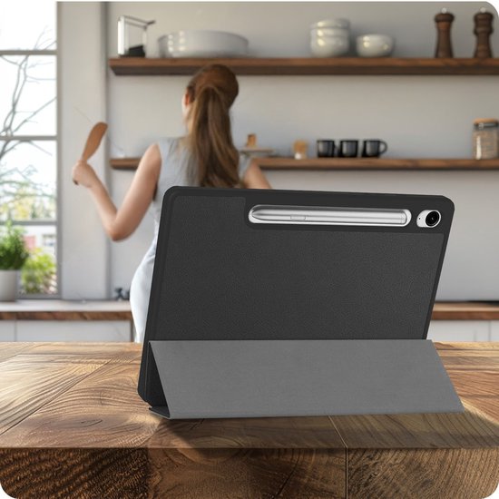 Zwarte tablethoes met S Pen houder, staand op een houten tafel in een keuken.