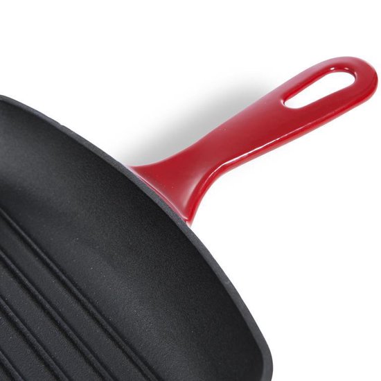 Detail van een zwarte gietijzeren grillpan met een rode handgreep.