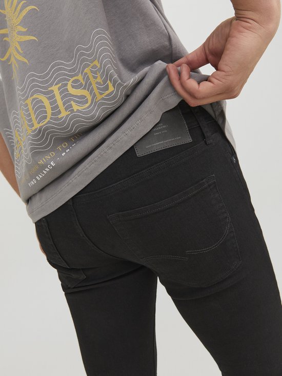 Achterkant van een strakke zwarte jeans met label, gedragen door man