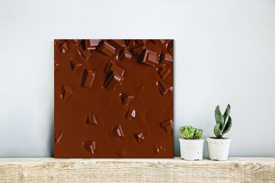 Gros plan de chocolat fondu avec des morceaux cassés, sur une étagère au-dessus de petites plantes.