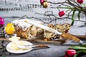 Paasbrood met poedersuiker en rozijnen, gesneden, met een broodmes met olijfhouten handvat en boter.