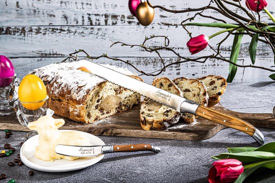 Paasbrood met poedersuiker en rozijnen, gesneden, met een broodmes met olijfhouten handvat en boter.