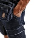 Dichtbij detail van de zakken en het materiaal van een donkerblauwe werkshort. Een hand steekt in een zak.