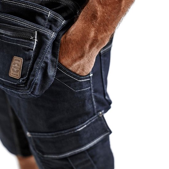 Dichtbij detail van de zakken en het materiaal van een donkerblauwe werkshort. Een hand steekt in een zak.