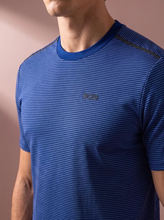 Close-up van een man in een blauw gestreept sportshirt met SJS-logo op de borst.