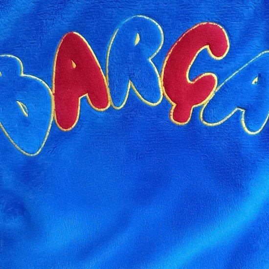 Close-up van de blauwe stof met de tekst 'Barça' geborduurd in opvallende rode en gele letters.