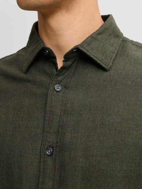 Close-up van de kraag en knoopsluiting van een donkergroen overhemd in flanel-stijl.