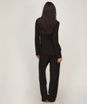 Achteraanzicht van model in een zwarte jersey pyjamaset met lange mouwen en rechte broek.