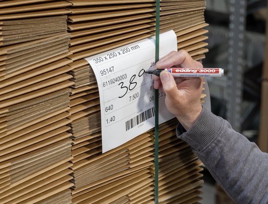 Hand schrijft 380 op label op stapel kartonnen dozen met edding 3000 stift.