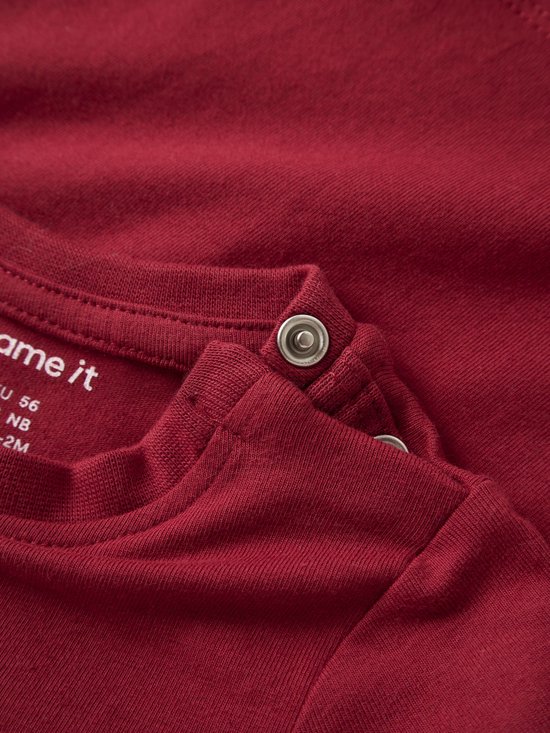Detail van bordeauxrood shirt met 'name it' label en zilveren drukknopsluiting bij de nek.
