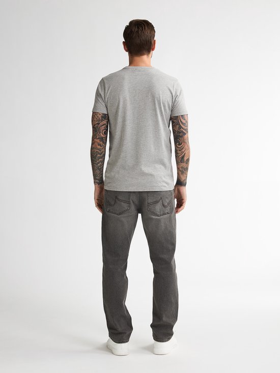 Model op de rug gezien, draagt een grijs T-shirt en grijze jeans, getatoeëerde armen zichtbaar.