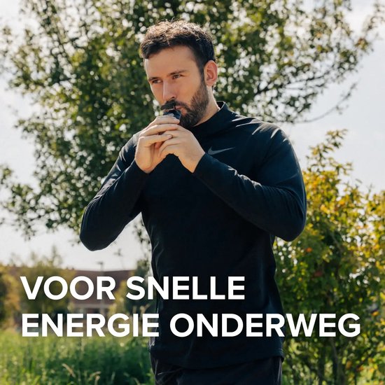 Man met baard in zwart hardloopshirt neemt een Pure. Energy Gel tijdens het sporten buiten.