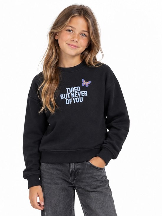 Zwarte trui met tekst 'TIRED BUT NEVER OF YOU' en een vlinderopdruk. Een meisje draagt de trui met een spijkerbroek.