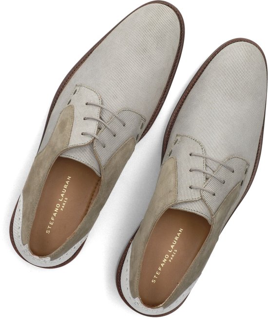 Bovenkant van een paar lichtbeige nette schoenen met suède en witte details.