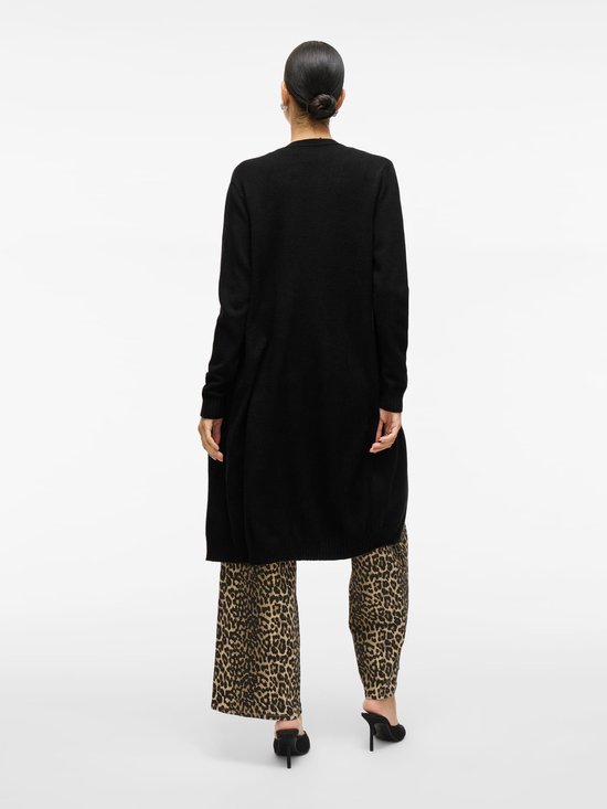 Achterkant van een vrouw in luipaardprint broek met wijde pijpen en zwarte lange vest.
