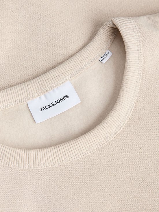 Close-up van de kraag en het Jack & Jones label in een crème kleurige sweater.