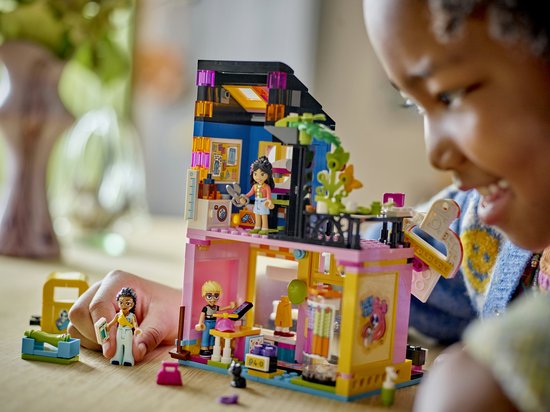 Enfant jouant avec le magasin de vêtements vintage LEGO Friends avec figurines.