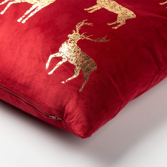 Detail van rood fluwelen kussen met gouden rendierprint en zichtbare ritssluiting.