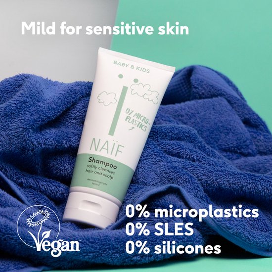 Naïf Shampoo op een blauwe handdoek, vegan-gecertificeerd, mild voor de gevoelige huid, 0% microplastics, SLES, siliconen.