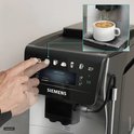 Vinger selecteert 'caffè crema' op het touchscreen van de zilverkleurige Siemens volautomaat.