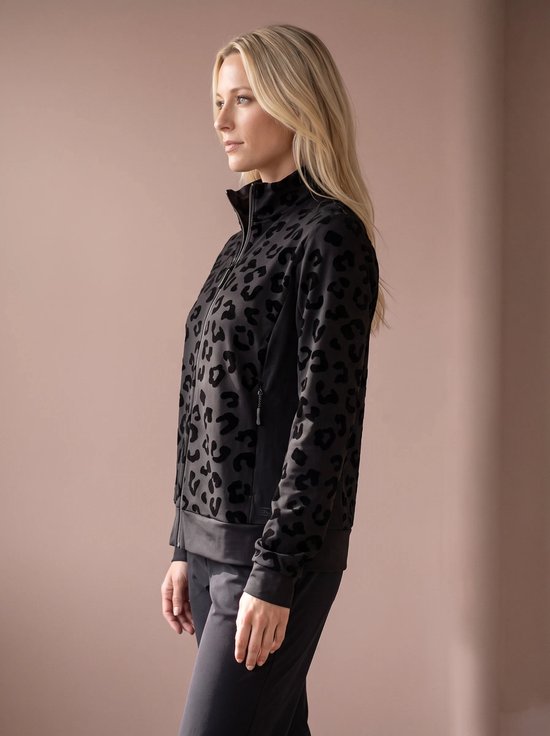 Zijprofiel van een model met blonde haren die een zwarte sportjas met zwarte panterprint draagt.