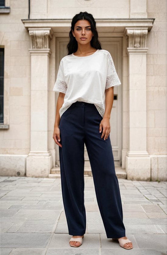 Model draagt wit T-shirt met kanten mouwen en een donkerblauwe wijde broek met hoge taille.