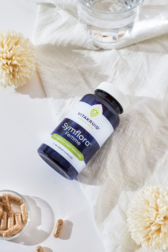 Vitakruid Symflora Femme blauwe pot met 90 vegan capsules, liggend naast een schaaltje capsules en bloemen.