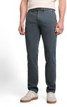 Man in een donkergroene chino broek, beige T-shirt en witte sneakers.