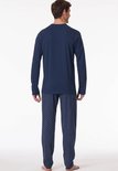 Man van achteren gezien in een marineblauwe pyjama met een effen shirt en een broek met ruitpatroon.