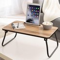 Houten bedtafel met tablet, notitieboekje en schaal met kommetjes.