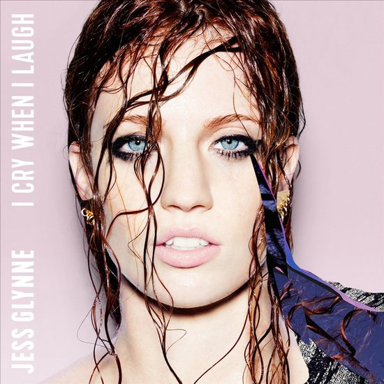 Jess Glynne, met nat haar, op de voorkant van het album "I Cry When I Laugh". Blauwe ogen, make-up, en een paarse glitterstof voor haar gezicht.