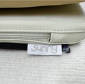 Label met 'Sunny' logo op een beige kussen met rits.