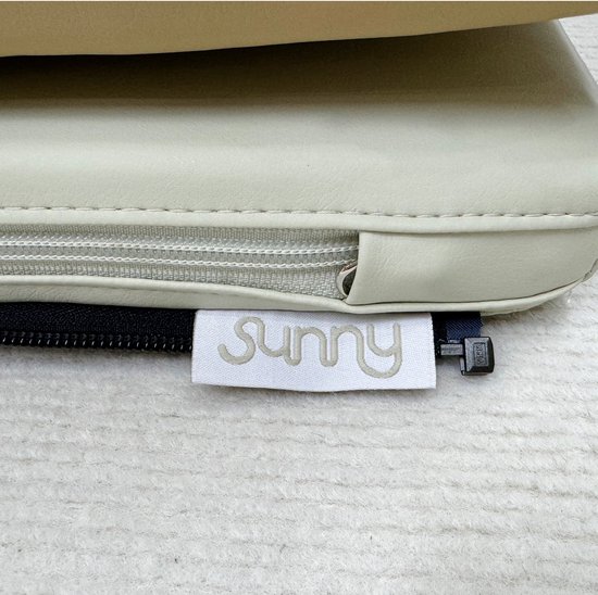 Label met 'Sunny' logo op een beige kussen met rits.