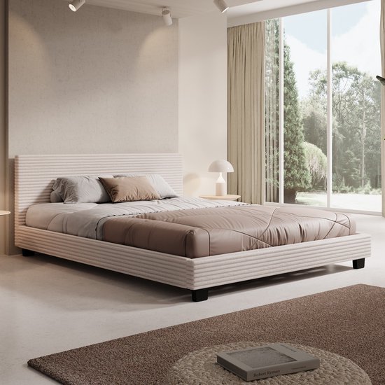 Lit avec tissu beige côtelé, tête de lit rembourrée et housse de couette taupe. Deux oreillers et un coussin d'accentuation marron.