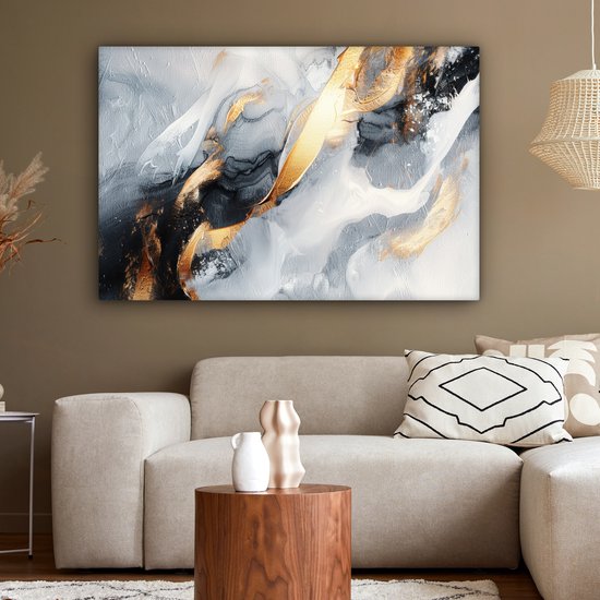 Abstract schilderij met gouden, grijze en witte vegen, hangend aan een bruine muur boven een beige bank.