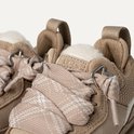 Close-up van beige UGG sneakers met stoffen veters met ruitpatroon en schapenwollen voering.