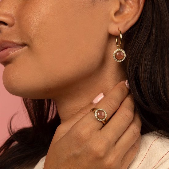 Gouden oorbellen met ronde, roze steen en zirkonia steentjes. Gedragen op een model.