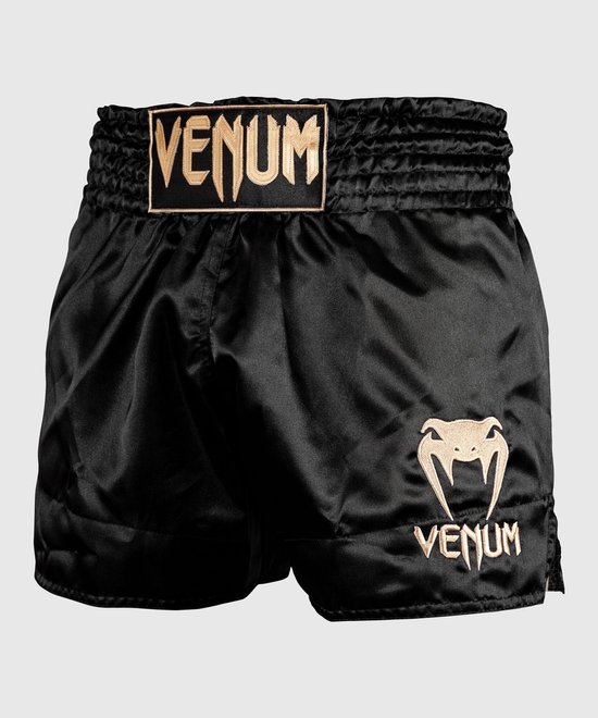 Zwarte satijnen Muay Thai shorts met goudkleurige Venum-logo's op de tailleband en broekspijp.