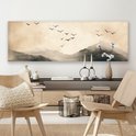 Une toile panoramique avec des montagnes et des oiseaux en vol, dans des tons sépia, au-dessus d'une commode avec des décorations.