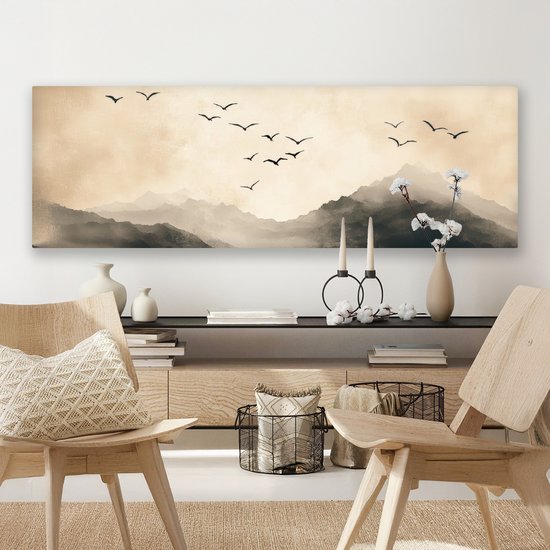 Une toile panoramique avec des montagnes et des oiseaux en vol, dans des tons sépia, au-dessus d'une commode avec des décorations.