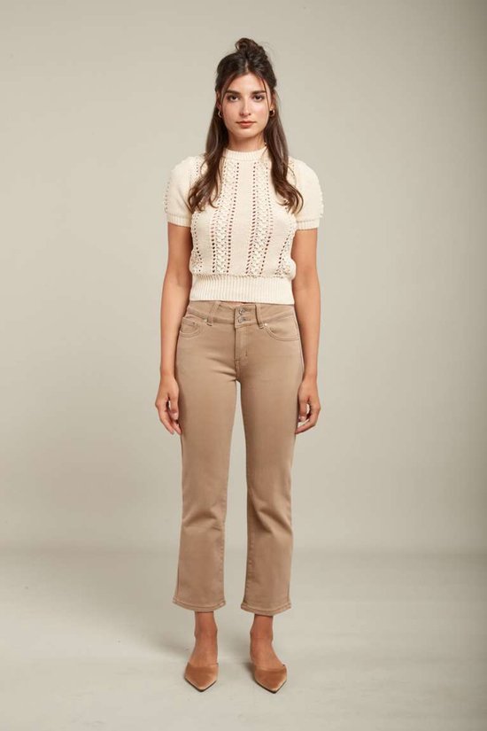 Model van voren in crème gebreide top met korte mouwen en beige jeans. Ze draagt puntige pumps.